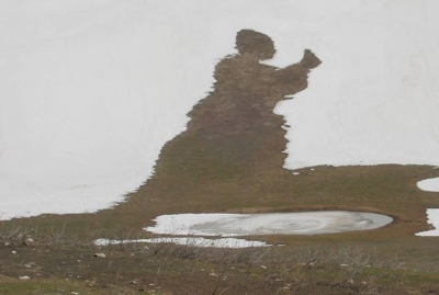 Un nomade in ginocchio mentre alza verso il cielo l’ostia della misericordia e recita: Laudato si’, mi’ Signore, per sora nostra matre Terra, la quale ne sustenta et governa, et produce diversi fructi con coloriti flori et herba. 