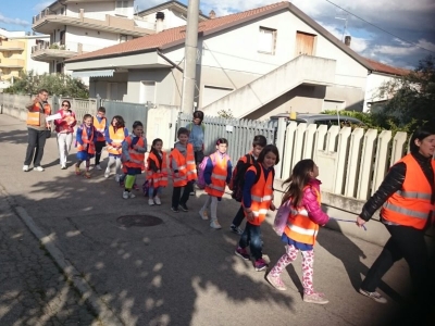 Una mamma che con il sorriso sulle labbra accompagna i bambini a scuola