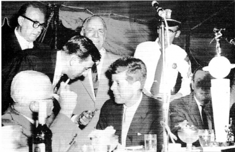 malandra in piedi accanto a JF Kennedy